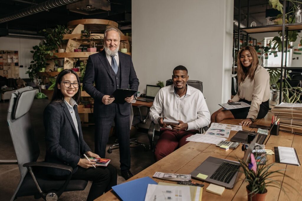 Diverse business team working together in a contemporary office setting with laptops and documents.